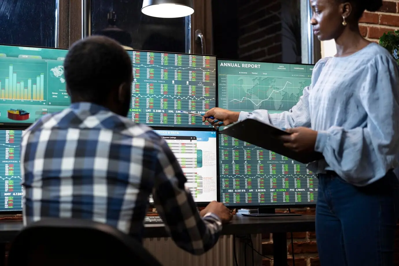 Männliche und weibliche Händler überprüfen Börsendaten.