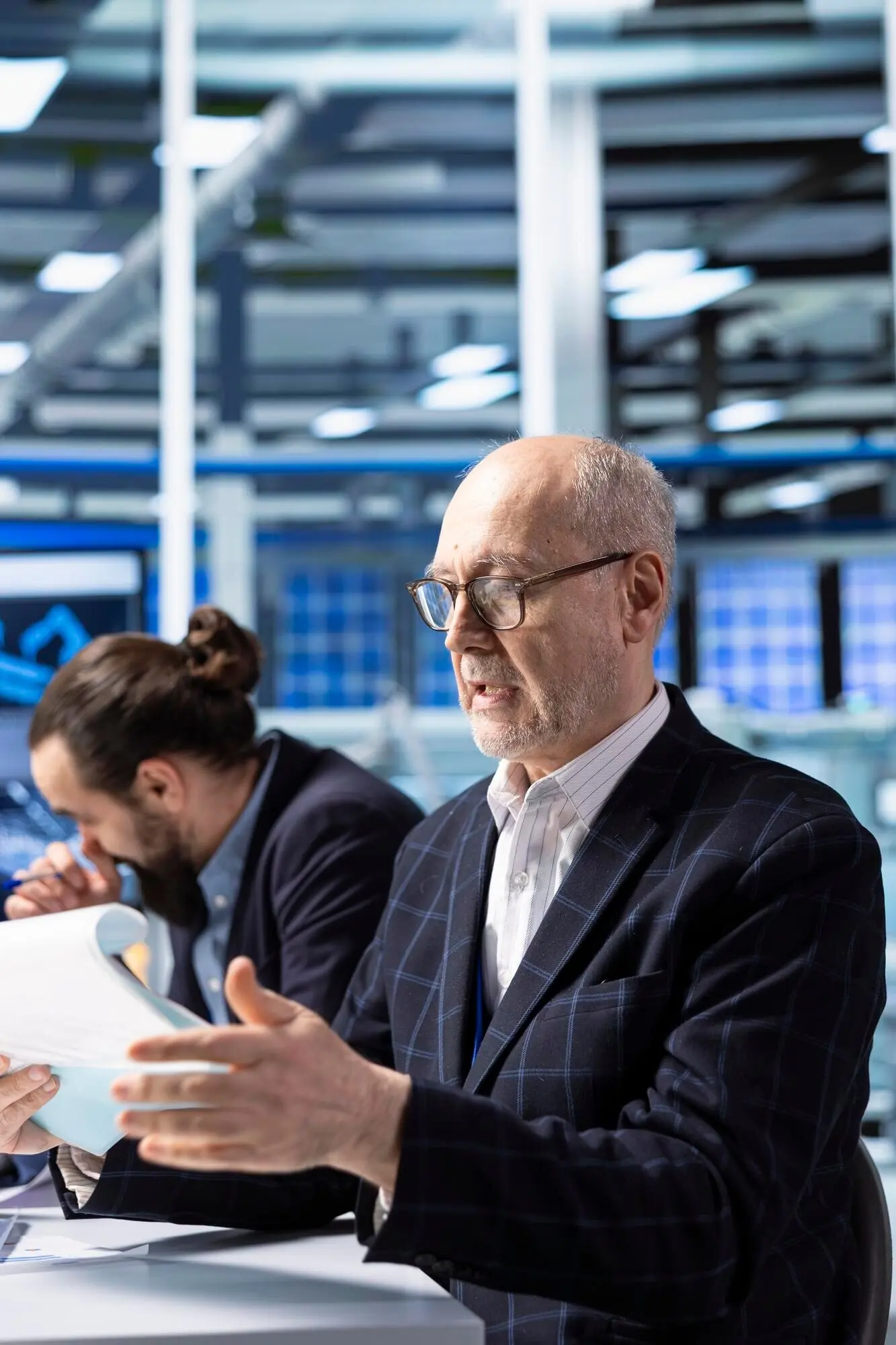 Hochrangiger Investor in einer Industrieanlage prüft Unterlagen vor Abschluss des Geschäfts.